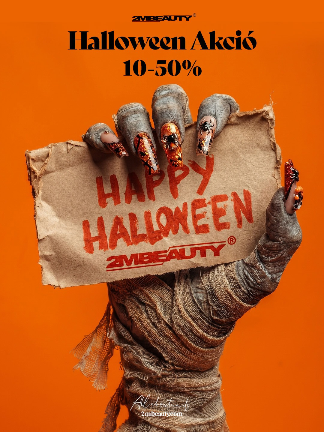Múmiakéz Halloween műkörömmel – narancs csillámos, pókos díszítésű körmök – Happy Halloween 2MBEAUTY feliratú papírlapot tart